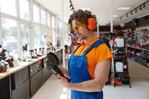 Male seller testing angle grinder at hardware store cropped shot. Shop assistant showcasing industrial manual electric tool for sale