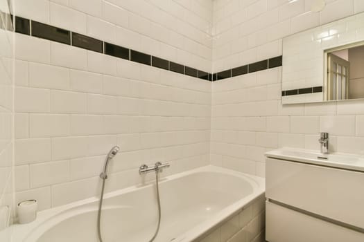A sleek and contemporary bathroom showcasing a white bathtub, stylish fixtures, and minimalistic design with black accents on tiles.