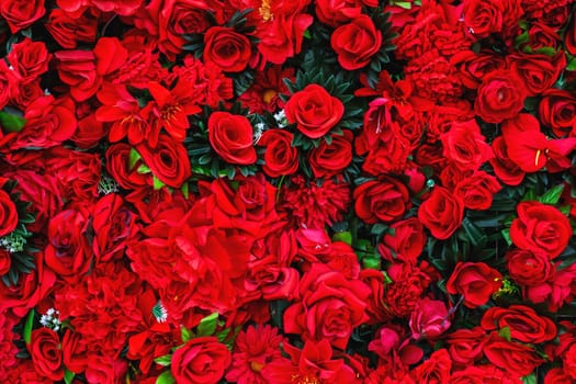 A beautiful bunch of vibrant red roses is gracefully arranged, sitting on top of each other on a lovely table, creating a charming display