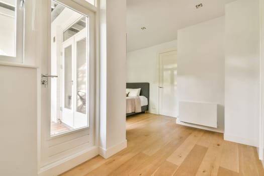 A stylish and airy interior featuring wooden flooring, white walls, and large windows. The minimalist design creates a serene ambiance perfect for relaxation.
