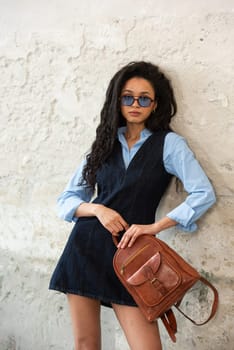 A fashionable model confidently showcasing a modern outfit while sporting a brown backpack accessory