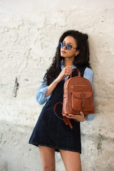 A fashionable model confidently showcasing a modern outfit while sporting a brown backpack accessory
