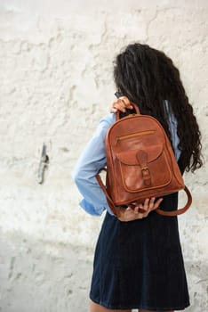 A fashionable model confidently showcasing a modern outfit while sporting a brown backpack accessory