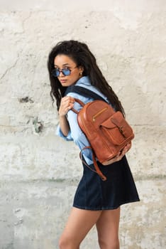 A fashionable model confidently showcasing a modern outfit while sporting a brown backpack accessory