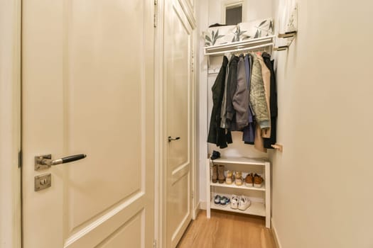 A modern hallway closet featuring neatly hung clothes and tidy shoe storage, blending functionality with contemporary design elements in a bright space.