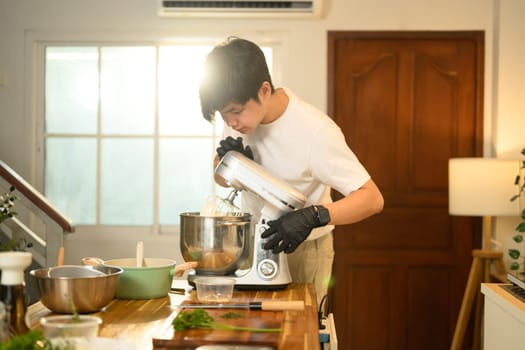 Young asian man checks the texture of whipped cream during home baking.