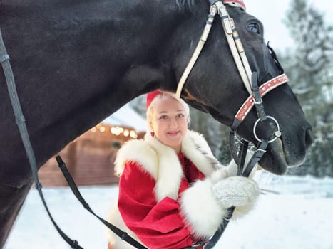 A Russian girl in traditional attire enjoys Maslenitsa festivities with a horse in the winter.