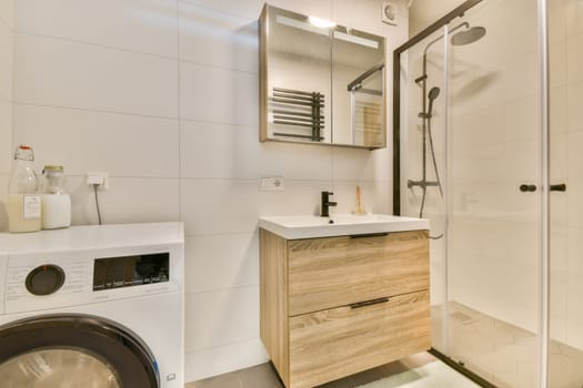 Contemporary bathroom featuring a stylish shower, wooden storage unit, and laundry equipment for a functional and aesthetic appeal.