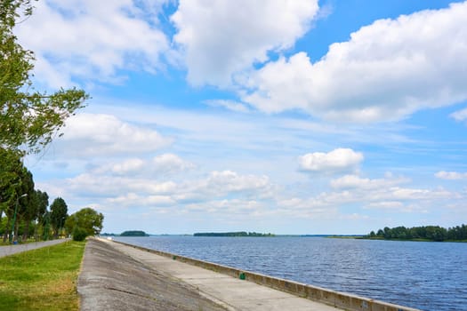 a wall or bank of earth or stone built to prevent a river flooding an area