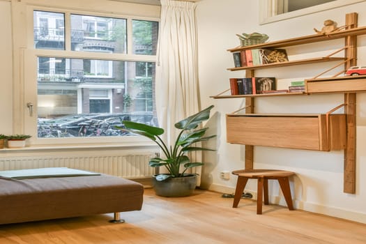 A stylish modern living room featuring a comfortable couch, wooden shelving, and large windows that allow natural light to enhance the ambiance.