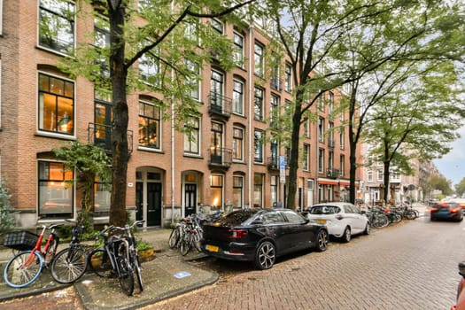 A picturesque view of a tree-lined street featuring classic brick buildings, parked bicycles, and cars, evoking a cozy urban atmosphere.