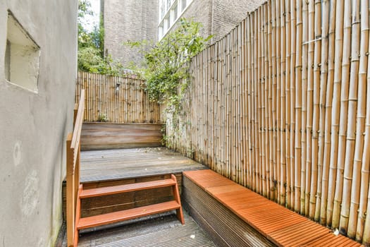A serene outdoor space featuring bamboo fencing and wooden steps leading to a cozy seating area, ideal for relaxation and tranquility in an urban setting.