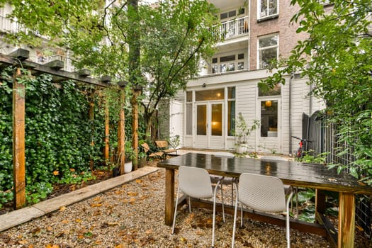 A tranquil urban garden showcasing a rustic dining table surrounded by lush greenery and adorned with a cozy atmosphere, perfect for relaxation and gatherings.