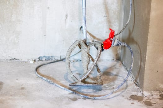 A vibrant hose featuring a bright red valve that is securely attached to it, contrasting its flexible form against its surroundings