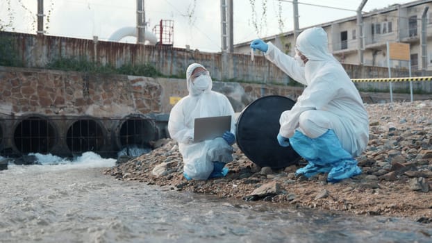 Ecologist sample water from the river and get fishes dead to check effected case in laboratory, Biologist wear protect suit and mask collects sample of waste water from industrial, problem environment
