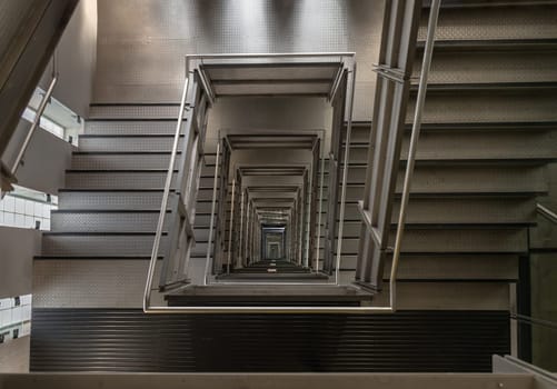 Newcastle, UK - Apr 11, 2025 - Looking down into the Square shaped Spiral staircase inside of Centre for Contemporary art in Baltic Flour Mills at Gateshead Quayside by the River Tyne. Placing mirrors at the top and bottom of the stairwell creates an illusion of a never ending stairs, use it as your Wallpaper, Poster and Copy space, Selective focus.