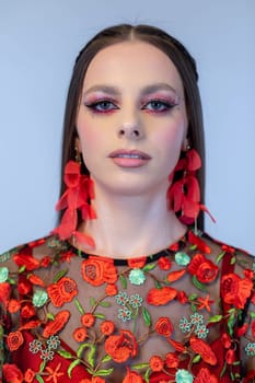This is a striking fashion portrait that showcases intricate floral embroidery along with bold, vivid makeup