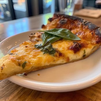 Pizza with cheese and basil on a white plate in a restaurant