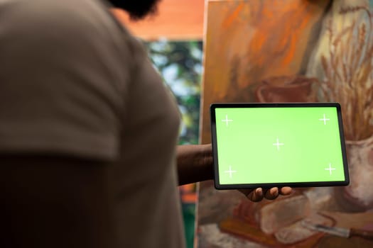 African american painter using a gadget with copy space screen in workshop, working on his new nature inspired masterpiece on canvas. Using watercolor paint and creativity in atelier.