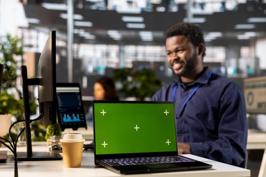 African american male worker creates business strategy next to isolated screen, analyzing data for a financial report. Global expansion project development, enterprise solutions.
