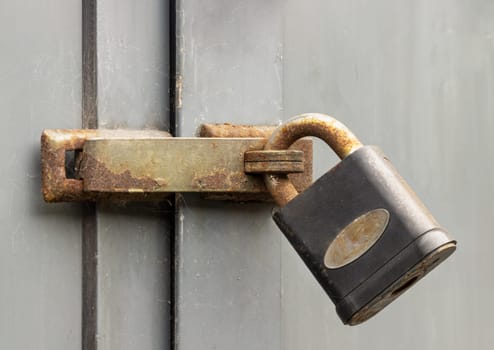 Newcastle, UK - Apr 13, 2025 - Metal locked padlock in Rusty iron door lock hasp latch on the Wooden door frame. Storage security, use it as your Wallpaper, Poster and Space for text, Selective focus.