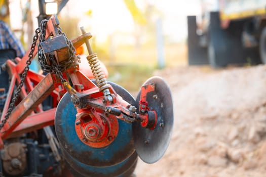 Close-up of modern disc harrow attachment on agricultural tractor in rural countryside. Essential farm machinery for soil preparation, improving field conditions, and enhancing crop growth efficiency.