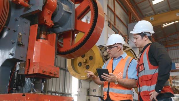 Two engineers talking together in roof steel metal manufacturing factory industry, engineering worker man standing explaining for maintain of metal sheet stamping machine, teamwork concept
