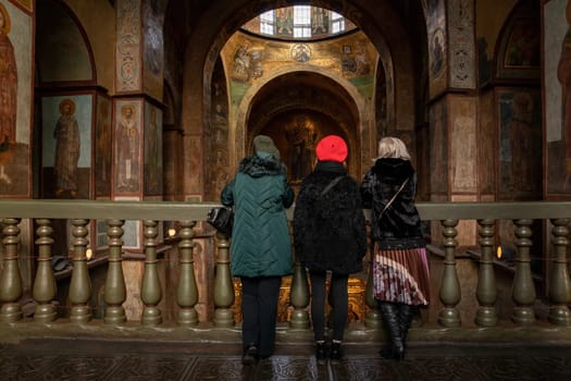 Three unrecognizable tourists examines the interior of the St. Sophia Cathedral in Kyiv Ukraine