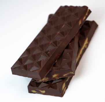 Stacked layers of kadaif embrace a generous coating of rich chocolate and are topped with a pistachio, showcasing the delightful texture and flavors in a culinary presentation.