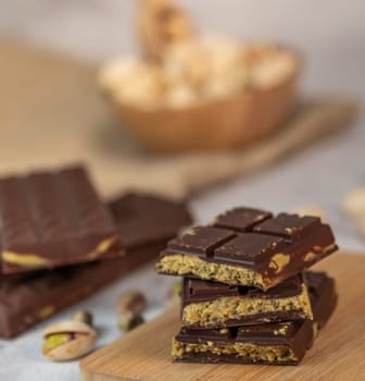 Gourmet chocolate mixed with crunchy kadaif pistachio pieces is beautifully presented on a wooden board, making a perfect treat in Dubai's culinary scene.