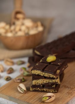 Gourmet chocolate mixed with crunchy kadaif pistachio pieces is beautifully presented on a wooden board, making a perfect treat in Dubai's culinary scene.