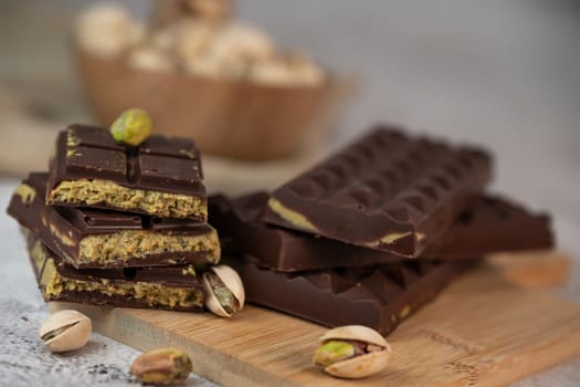 Gourmet chocolate mixed with crunchy kadaif pistachio pieces is beautifully presented on a wooden board, making a perfect treat in Dubai's culinary scene.