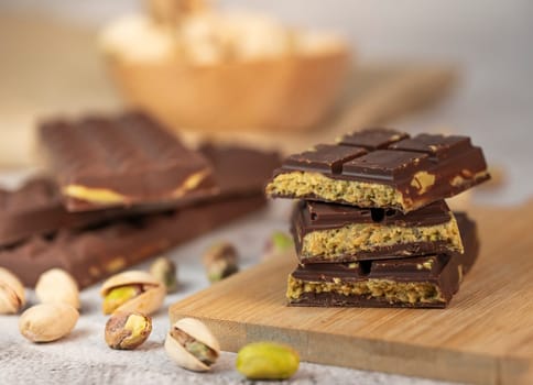 Gourmet chocolate mixed with crunchy kadaif pistachio pieces is beautifully presented on a wooden board, making a perfect treat in Dubai's culinary scene.