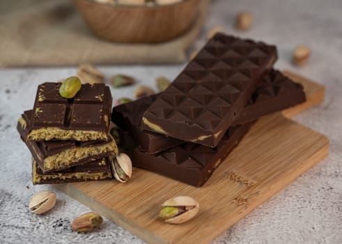 Gourmet chocolate mixed with crunchy kadaif pistachio pieces is beautifully presented on a wooden board, making a perfect treat in Dubai's culinary scene.