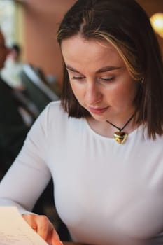 Young woman looking at the menu in a restaurant, beautiful brown-haired woman with short hair. High quality photo