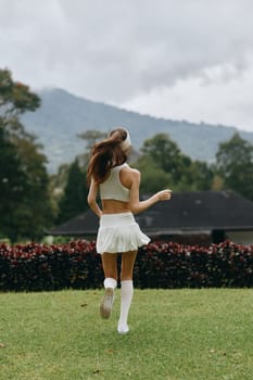 Energetic young model dressed in white activewear runs through a picturesque green park, reflecting joy, health, and an active lifestyle amidst a serene backdrop of nature