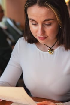 Young woman looking at the menu in a restaurant, beautiful brown-haired woman with short hair. High quality photo