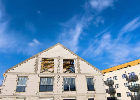 Unfinished new houses being built with white bricks in the city under a blue sky. High quality photo