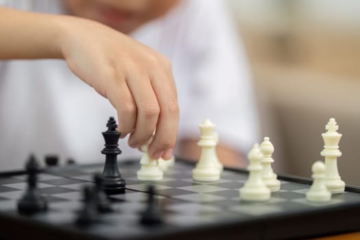 A mother guiding her son as they focus on chess strategy together, fostering educational interaction at home.