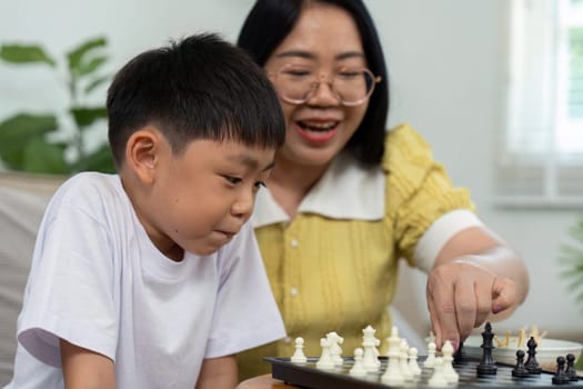 A mother and her son enjoy a fun game of chess together, sharing laughter and bonding over strategy in their cozy living room.