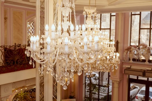 huge and luxurious chandelier on the ceiling in the hall. Elegant crystal chandelier with flame-shaped bulbs in a formal setting.