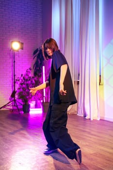 A dancer showcases their skills in a brightly lit studio with soft purple and yellow background lights. The atmosphere is energetic and artistic, enhancing the performance.