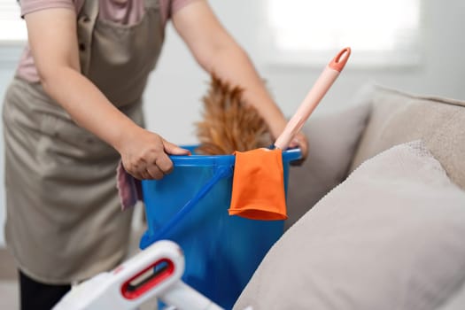 The woman is seen arranging her cleaning tools in a blue bucket, showing her commitment to maintaining a clean and organized home environment.