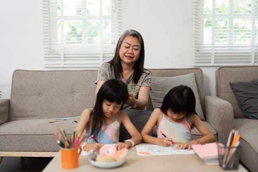 A grandmother lovingly engages with her granddaughters as they create art, fostering a supportive and creative environment at home.