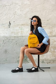 A fashionable model confidently showcasing a modern outfit while sporting a yellow backpack accessory