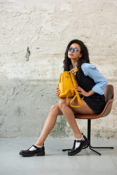 A fashionable model confidently showcasing a modern outfit while sporting a yellow backpack accessory