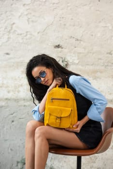 A fashionable model confidently showcasing a modern outfit while sporting a yellow backpack accessory