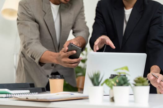 During a meeting, two professionals collaborate using a smartphone and laptop, showcasing modern communication methods in a business setting.