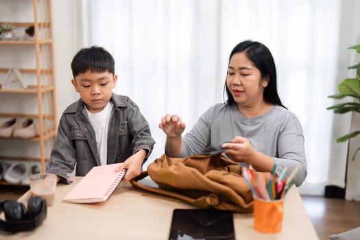 A mother assists her son in organizing his school supplies, ensuring he is ready for the upcoming school year while fostering a sense of responsibility.