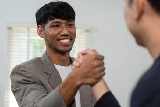 Two business professionals shake hands, symbolizing a successful partnership or agreement. The setting reflects a professional atmosphere, highlighting collaboration.